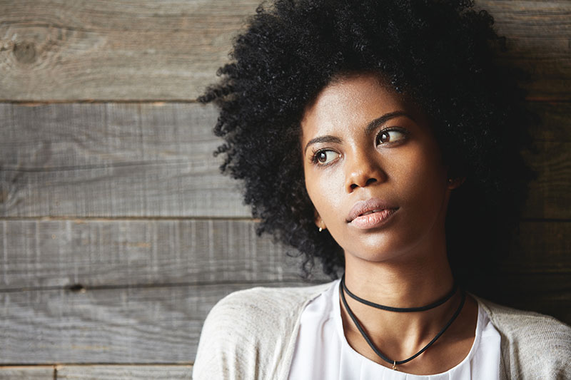 Woman resting head on crossed arms with a concerned look.
